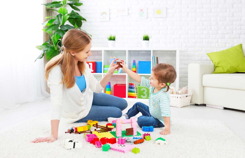 Woman and child playing with toys on the floor