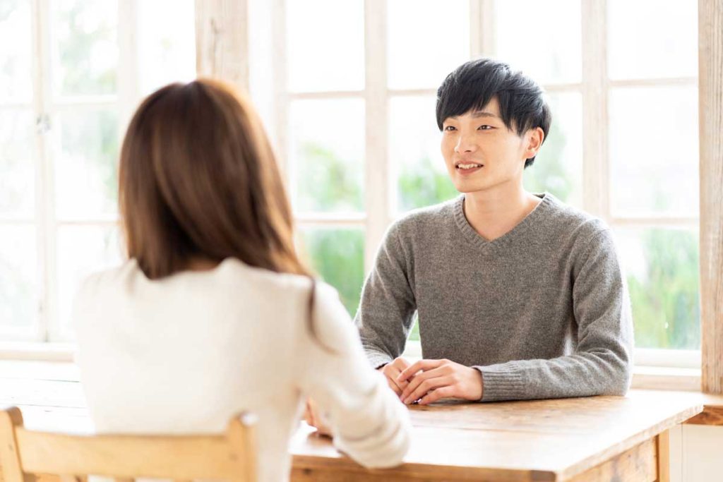 Young caucasian woman speaking to a young Chinese man